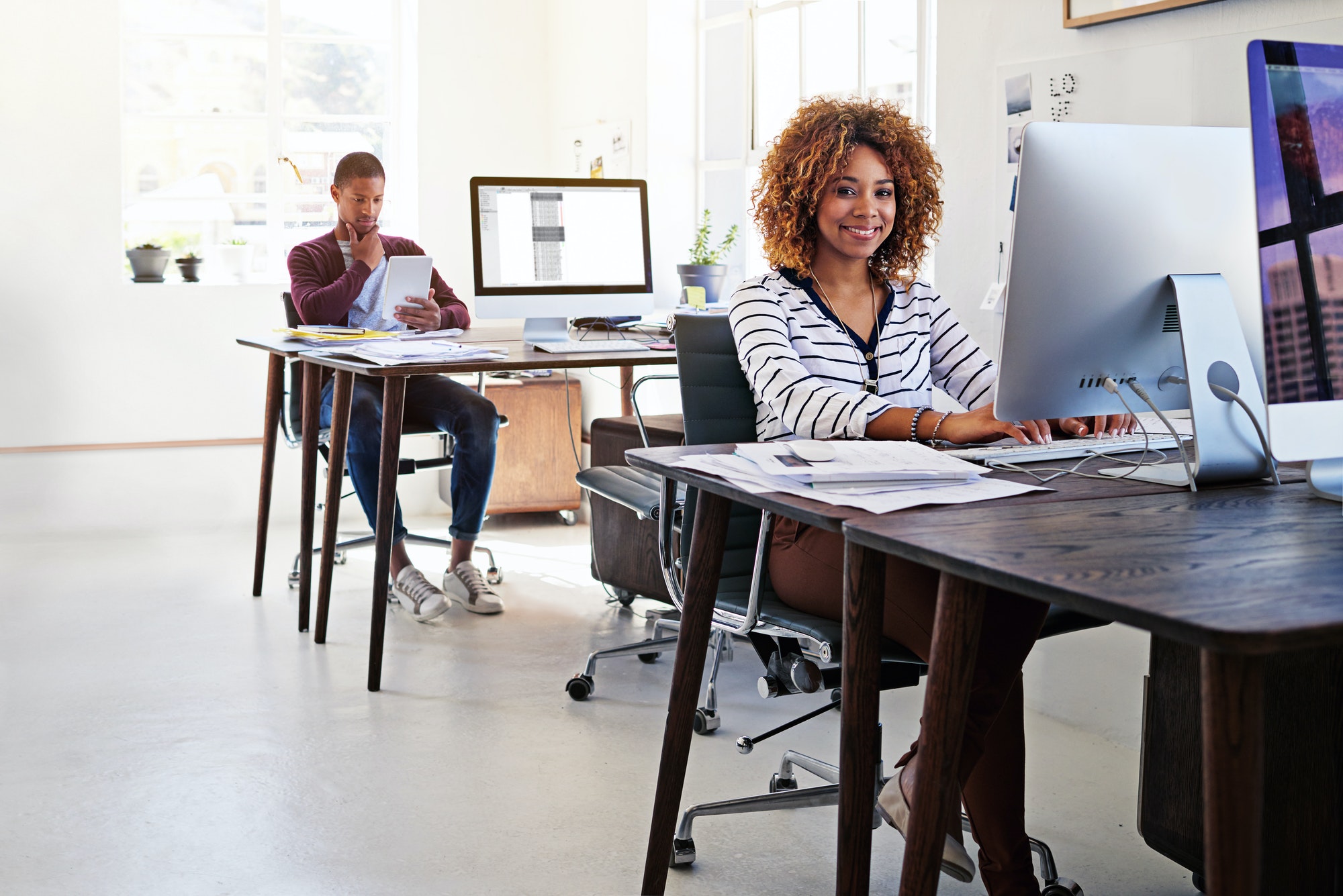 Open plan works for us. Portrait of a young woman working on her computer in an open plan office.